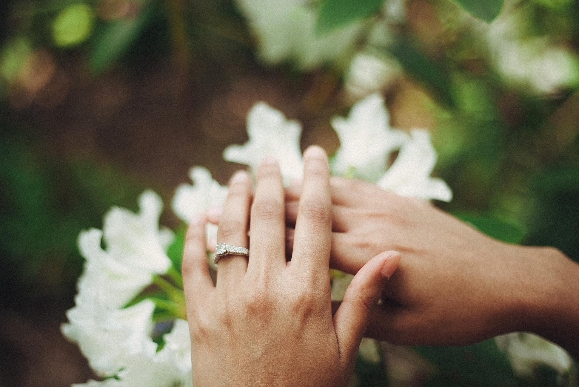 Bride and groom hands above bouquet